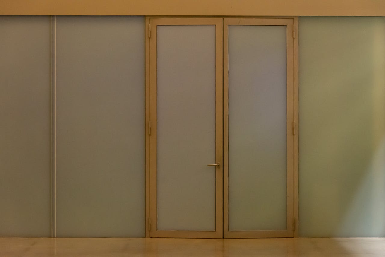 A minimalist beige door with frosted glass panels creating a modern aesthetic in an indoor setting.
