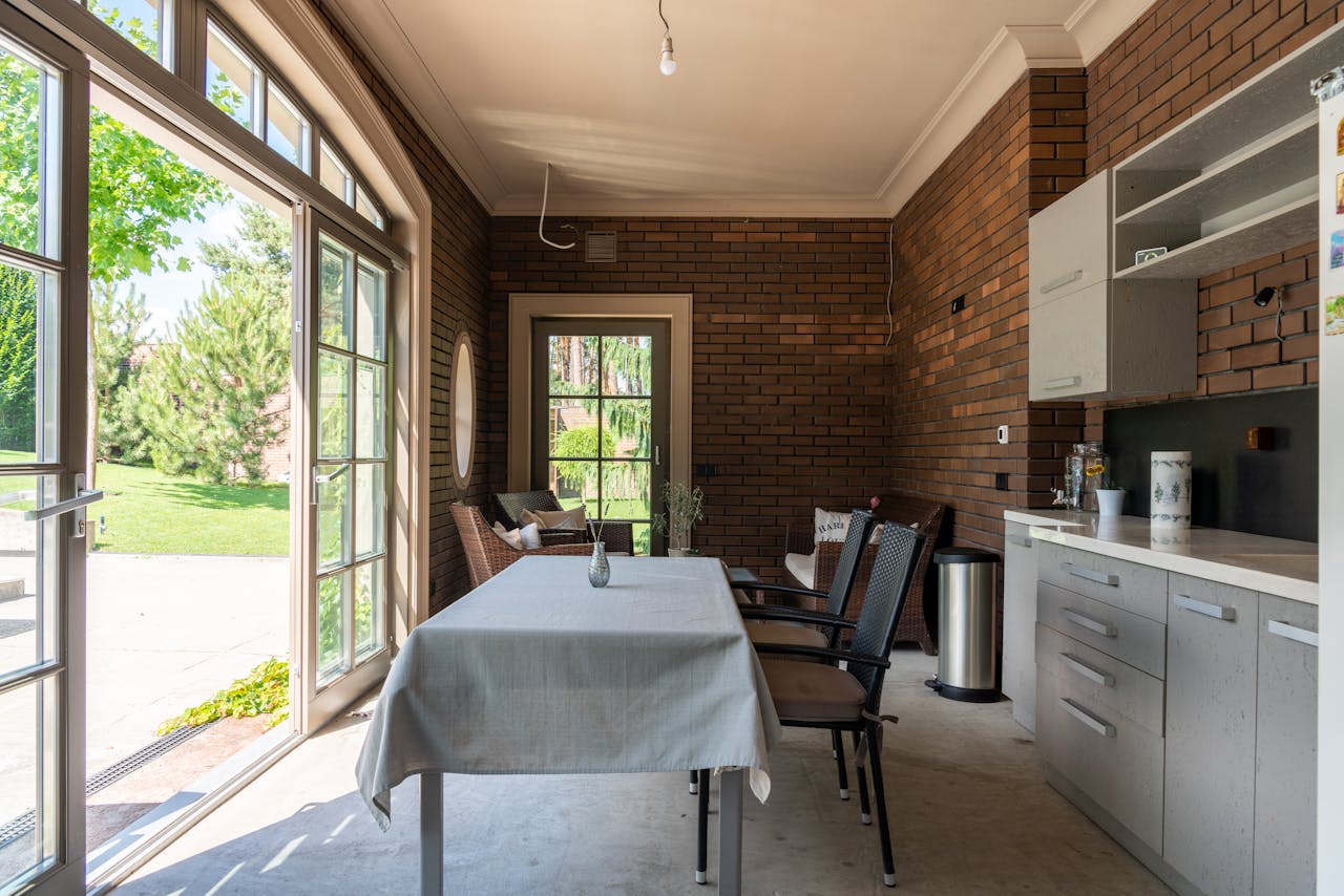 Bright dining area with a garden view, featuring brick walls and modern furniture.